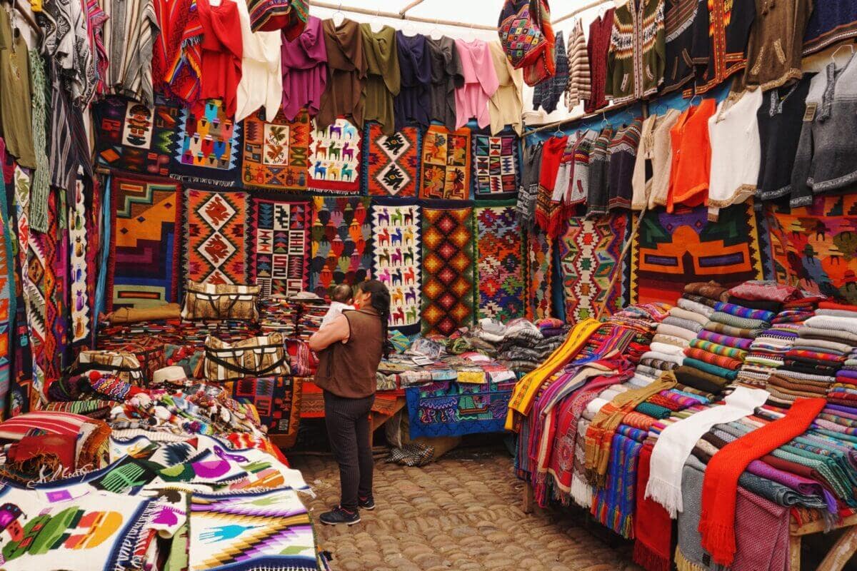 woman in store with display of assorted shirts and textiles