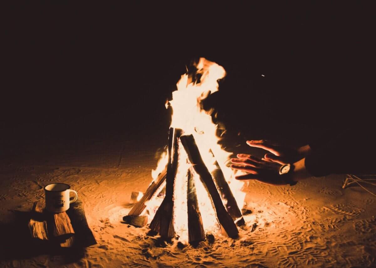 person heating hands beside bonfire at nighttime